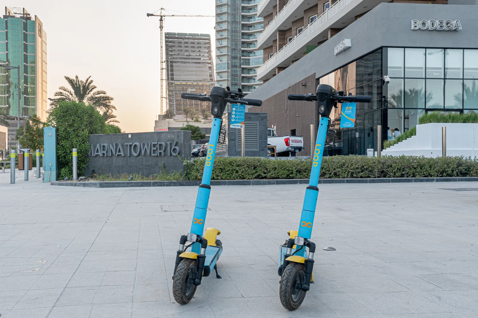 Two blue and yellow Loop scooters parked on a plaza in Qatar