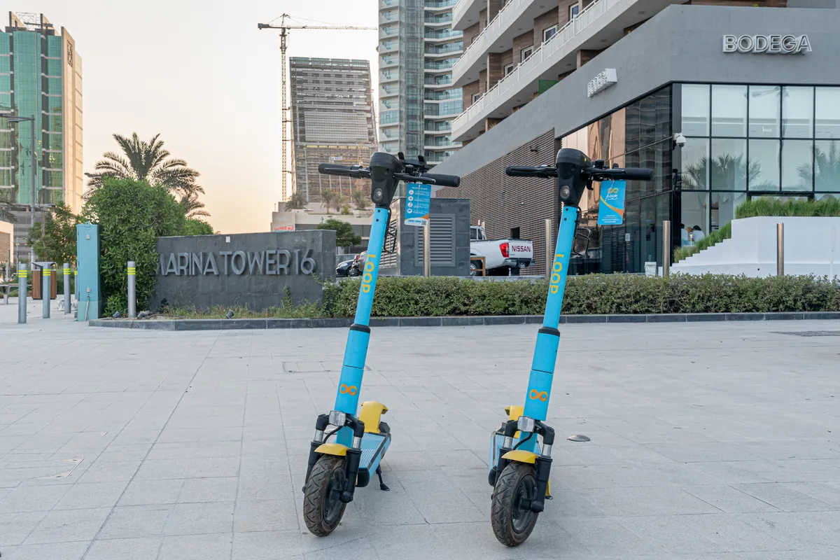 Two Loop scooters upright on their stands in a Qatar plaza